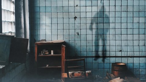 Hanging Man Shadow on Wall 4K Loop features an abandoned looking room with dust and debris in the air and the swaying shadow of a man hanging on the wall.