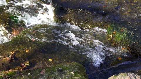 Closeup of a beautiful flowing river over rocky moss.