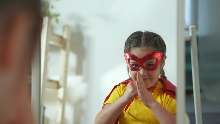 Girl in superhero mask. Child in hero costume. Happy child is winner. Girl is playing at home.Kid in front of mirror in hero mask.Girl play in superhero costume.Successful child with smile on his face Royalty-Free Stock Footage #1079769335