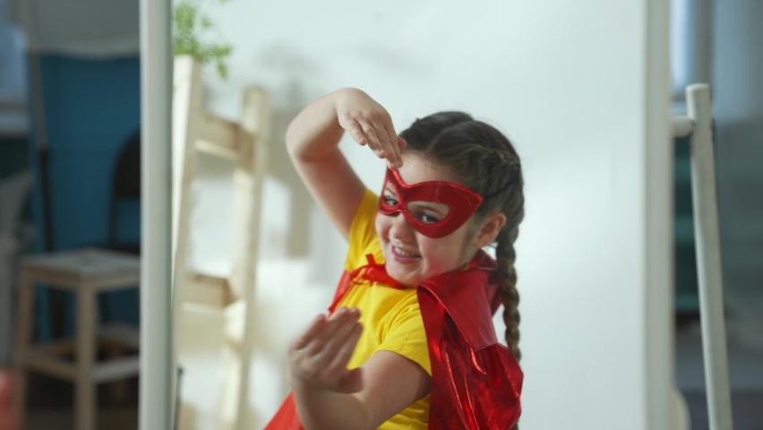Girl in superhero mask. Child in hero costume. Happy child is winner. Girl is playing at home.Kid in front of mirror in hero mask.Girl play in superhero costume.Successful child with smile on his face | Shutterstock HD Video #1079769335