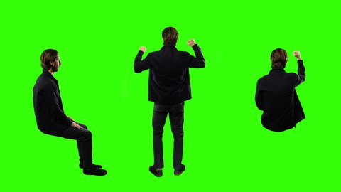 Man Celebrating Standing And Sitting On Green Screen Background. Man celebrates standing and sitting on a green screen background for replacement. Shot from behind and side