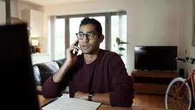 Mixed race business man chatting on cellular device working from home office