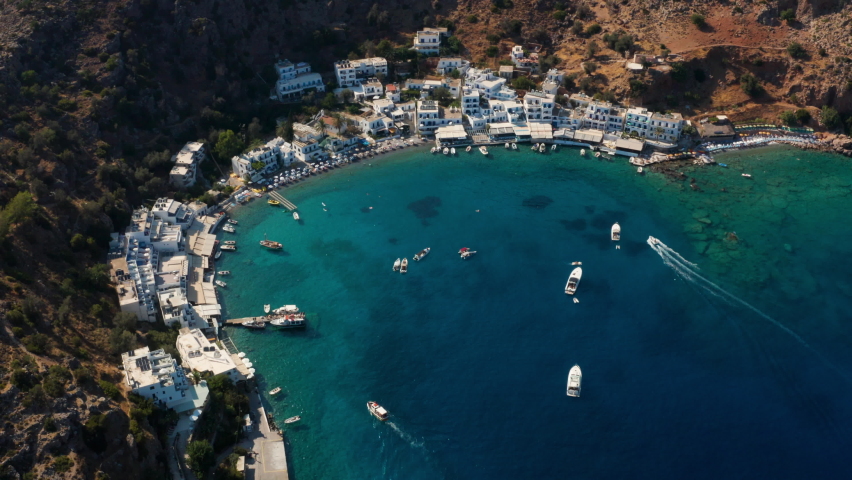 Boats And Yachts Floating On Clear Blue Sea Near Loutro Beach And Village In Crete, Greece. - aerial