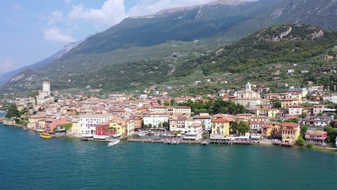 Aerial video view from waterfront of the historic city of Malcesine, the Scaliger Castle in Malcesine, the port and restaurants of old town, on the eastern shore of Lake Garda , Italy - K4 movie