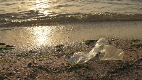 Plastic bottle by the sea at sunrise. The ecological disaster of the modern world is the pollution of seas and oceans with plastic waste.