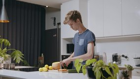 Caucasian young blonde male chopping vegetables in kitchen preparing meal for wife and kids