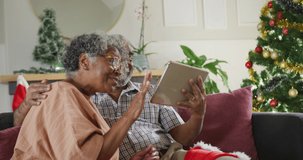 happy african american senior couple having video call at christmas time. christmas, festivity and communication technology.
