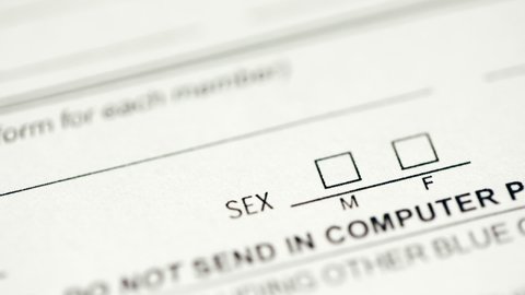 Person checking the male gender box on a document form with red ballpen