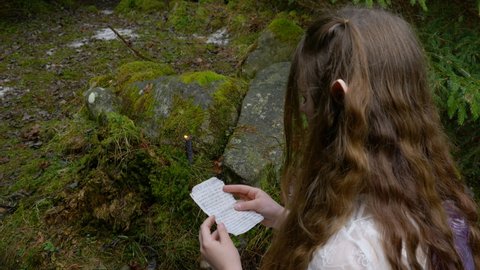 An elf girl in a white dress opens an envelope with letters in the forest. Fantasy concept. Ultra 4K