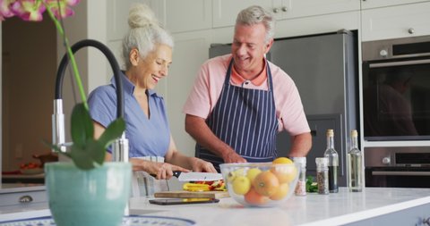 Caucasian senior couple wearing aprons cooking together in kitchen. 