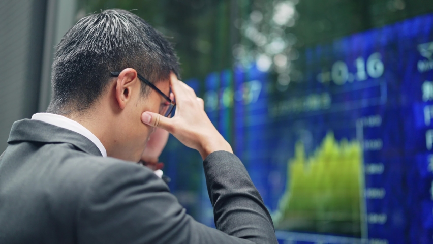 Depressed businessman in front of an electric bulletin board. Japanese translation: "yen","dollar","euro","pound" Royalty-Free Stock Footage #1079781398