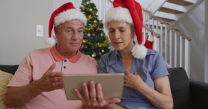 Happy caucasian senior couple having video call at christmas time.