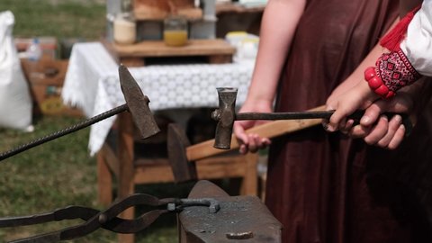 Close-up of forging a horseshoe. The blacksmith teaches the apprentice to knock on a red-hot horseshoe with a hammer. Training in blacksmithing.