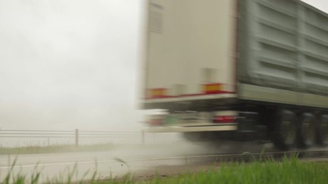 Semi-trailer semitrailer transports cargo on a wet road from rain in summer, close-up. Slippery road, trucking industry