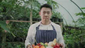 Portrait of young successful japanese farmer holding basket full of organic vegetables. Greenhouse happy worker collecting harvest products for market. - Powered by Shutterstock - Get 15% off with code: PIKWIZARD15