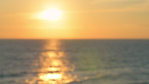 Defocused out of focus bokeh blurry sunset yellow golden color in Seaside, Santa Rosa Beach, Florida in panhandle gulf of mexico ocean with waves and reflection of sun path in water surface