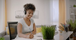 Lateral Dolly of Happy Young African American Woman Working or Studying on Laptop Computer from Home. Video Conference Call at Home Office. Online Learning or Teleworking Concept.