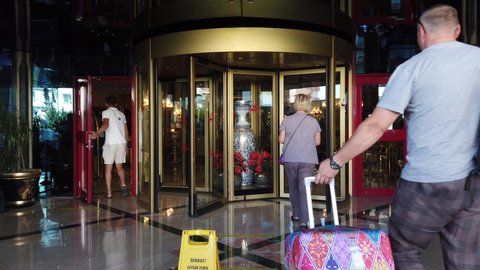 Turkey, Antalya, 20 August-2021. Spinning door hotel entrance, people passing through the revolving door of the modern hotel. Revolving door in reception of resort.