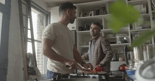 Hispanic male couple cooking in kitchen and looking at smartphone