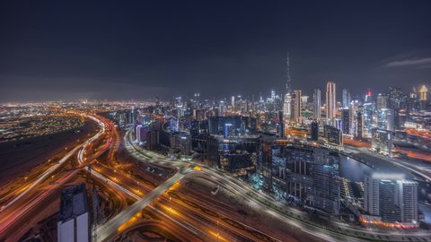 Panoramic skyline of Dubai with business bay canal and downtown district night timelapse. Aerial view of many modern skyscrapers and busy traffic on al khail road. United Arab Emirates.