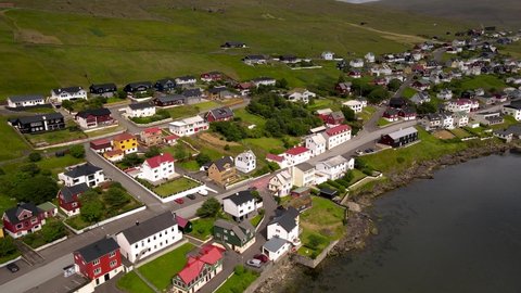 Beautiful aerial view of the town of Miovagur in the Faroe Islands, with its :churchs, grass roofs and colorful Houses in front of the ocean	