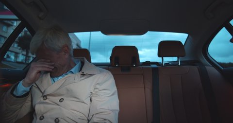 Stressed sad aged man crying in backseat of taxi. Portrait of senior depressed man sitting on backseat of car and crying feeling frustrated
