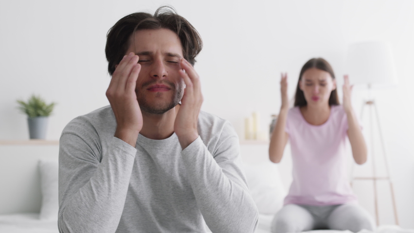 Relationship crisis. Discontented wife blaming unhappy husband at home, tired man feeling bored, couple having quarrel and marital problems, selective focus, slow motion