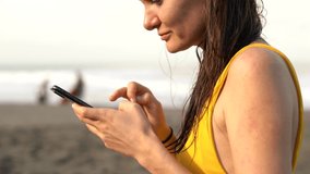 Cropped view of female sitting near ocean on summer vacation leisure using 4G internet connection for chatting online, close up video of woman millennial typing text messages and mails on mobile phone
