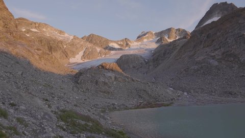Panoramic View of Vibrant Colorful Glacier Lake up in Rocky Mountains in Canadian Nature Landscape. Sunny Summer Sunset. Wedgemount Lake Hike in Whistler, British Columbia, Canada. Slow Motion