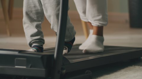 Optimistic Asian mother walking and running on treadmill with son during fitness workout at home