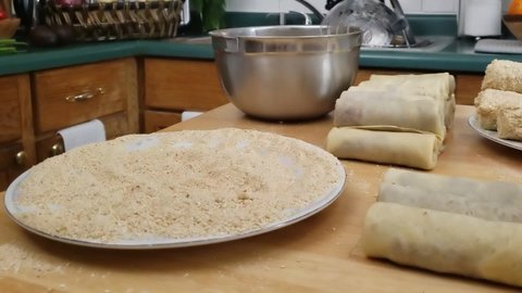 Home cooking - Close up and time lapse of covering omelet rolls with meat stuffing in batter and then in bread crumbs making croquettes ready for cooking or frying.