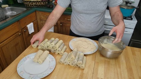 Home cooking - Covering omelet rolls with meat stuffing in batter and then in bread crumbs making croquettes ready for cooking or frying.