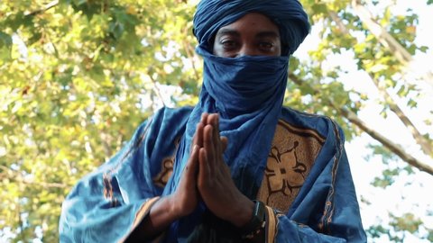 Errachidia, Morocco: 28-09-21:Man in traditional blue Tuareg dresses, danced in a park. Blurred background of trees.