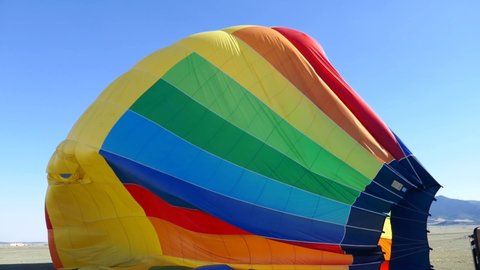 Deflated rainbow colored hot air balloon laying on side