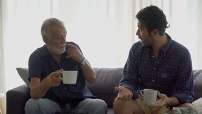 Senior Father and adult son drinking coffee and talking  together on sofa in the room at home . two generations family male  - Powered by Shutterstock - Get 15% off with code: PIKWIZARD15