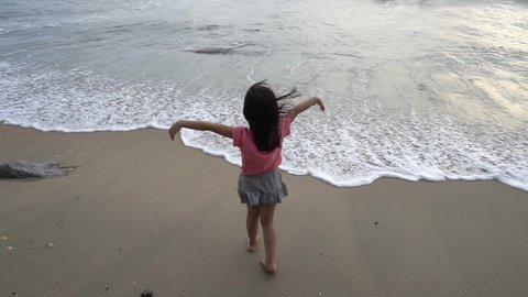 Slow motion little girl with bare foot wear face mask enjoy the gentle sea wave at beach