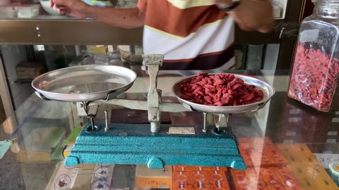 Thailand - September 2021: Measuring dried goji berry using traditional Chinese pharmacy scale medicine weight in Chinese herbal shop