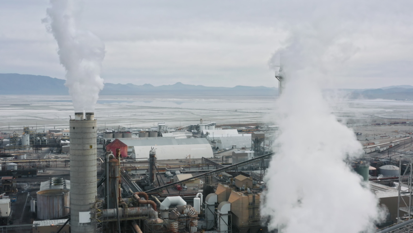 Chemical plant pumping out smoke and steam. Industrial air pollution and global warming disaster caused by the greenhouse effect. Sears city aerial panorama, California, United State of America 4K