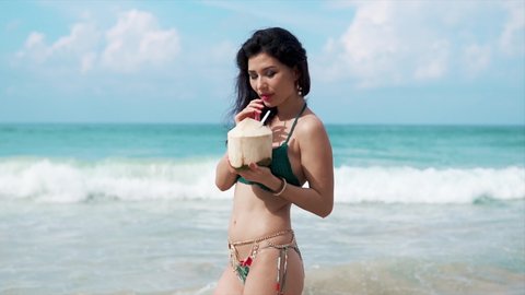 Beautiful girl drinking coconut on a beach. Tourism and recreation in Thailand. Charming cute Asian woman travel around the islands. The girl enjoy life and has fun. Paradise beaches and white sand