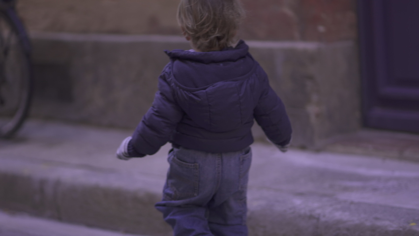 Toddler child walking outside in urban street sidewalk