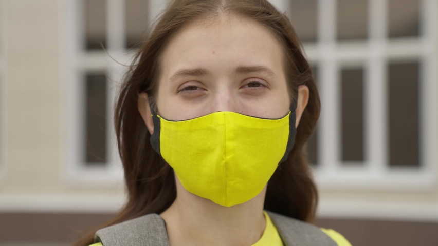 An adult schoolgirl puts on a face mask and smiles, pandemic 2022, filter air for the respiratory tract of the lungs, prevent COVID-19 infection, protect a person from coronavirus with a mask mode Royalty-Free Stock Footage #1079828993