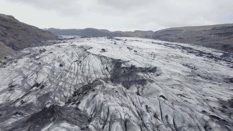 Aerial view over the Solheimajokull Glacier, in dark, cloudy Iceland - reverse, drone shot