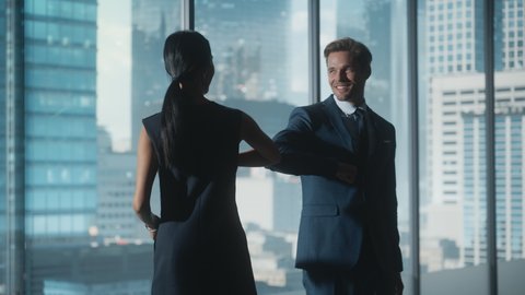 Female and Male Business Partners Meet in Office, Greeting with Elbow Bump. Corporate CEO and Finance Manager in City Office. Businesspeople Discuss Real Estate Purchase and Marketing Projects.