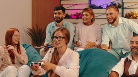 A big group of people are sitting in comfortable chairs and relaxing together as they play games using their controllers. Arri Alexa Mini.