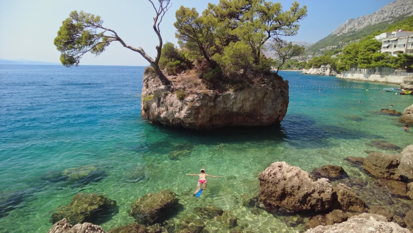 Woman in bikini, snorkeling in Punta Rata beach in Croatia around the famous Brela stone or Kamen Brela. Swimming in Croatian Adriatic Sea in the Split-Dalmatia County of Croatia in Europe. | Shutterstock HD Video #1079841548