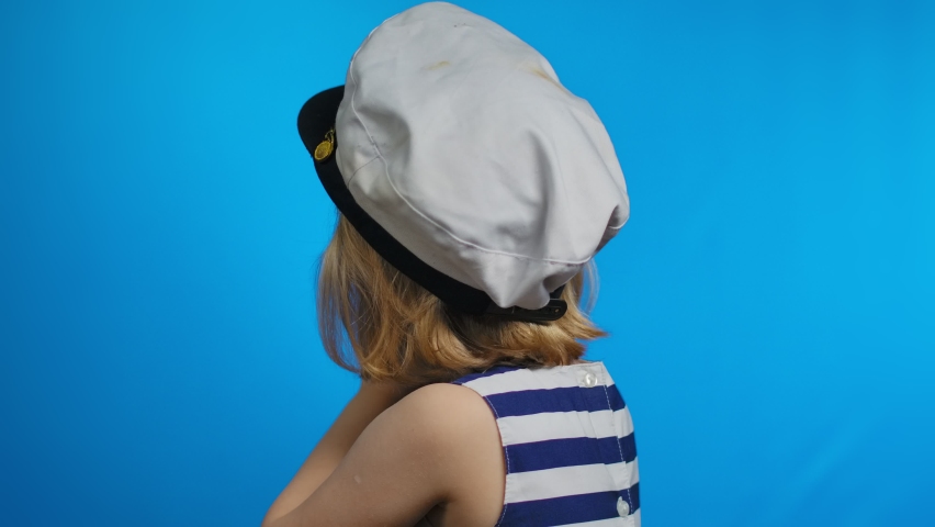 Cute girl in a sailor dress is using a retro photo camera for shooting pictures