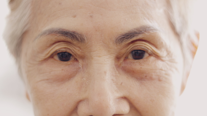 Face close up and 4K slow motion of asian senior lady who is 80 years old grandmother with high key style of bright background shows beautiful detail of wrinkle skin, black eyes and grey hairs. | Shutterstock HD Video #1079844221