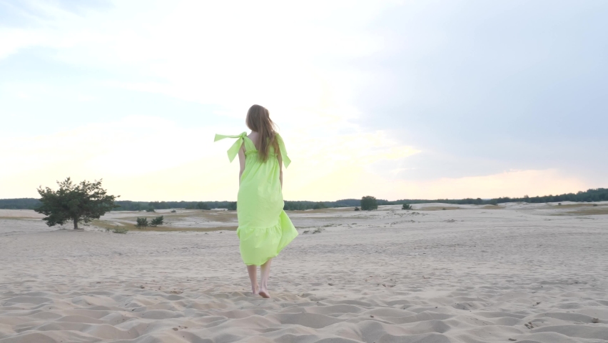 beautiful girl in sunglasses and stylish outfit smiles, walks and runs in the desert
