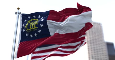 the flag of the US state of Georgia waving in the wind with the American stars and stripes flag blurred in the background. Seamless animation. Us state flag