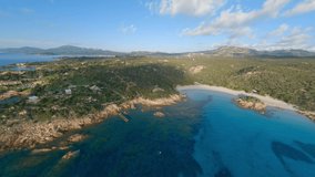 FPV video, view from above, aerial view from an FPV drone flying at high speed over a green coast with a beautiful white sand beach bathed by a turquoise water. Prince Beach (Spiaggia del Principe)